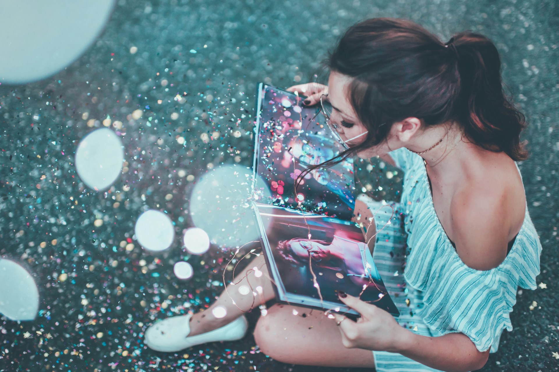 Woman sits blowing glitter off the page of a book